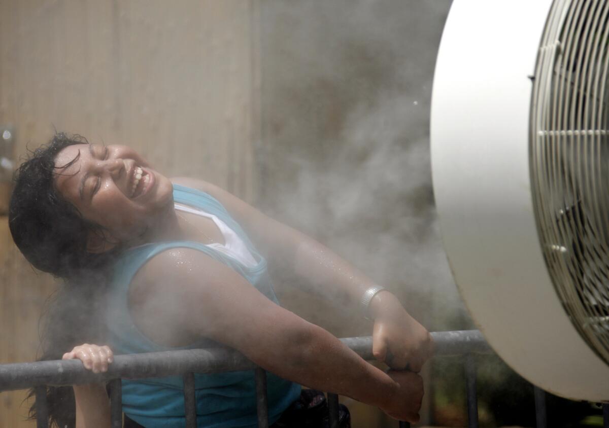 Cynthia Henriquez, 8, cools off from the heat in the mist of a fan set up for visitors at the Los Angeles Zoo on Wednesday, July 26, 2006. Starting Thursday, warmer weather will plague California.
