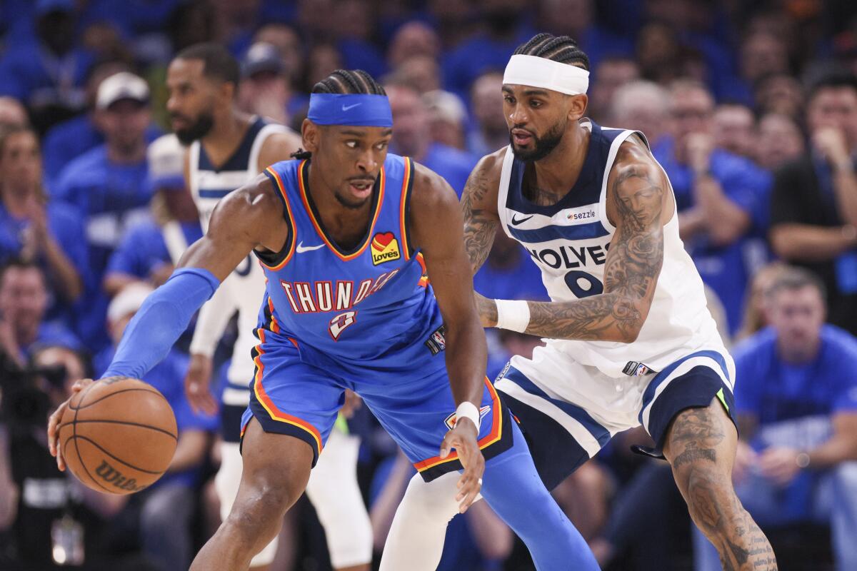 Thunder guard Shai Gilgeous-Alexander, left, is tightly defended by Timberwolves guard Nickeil Alexander-Walker.
