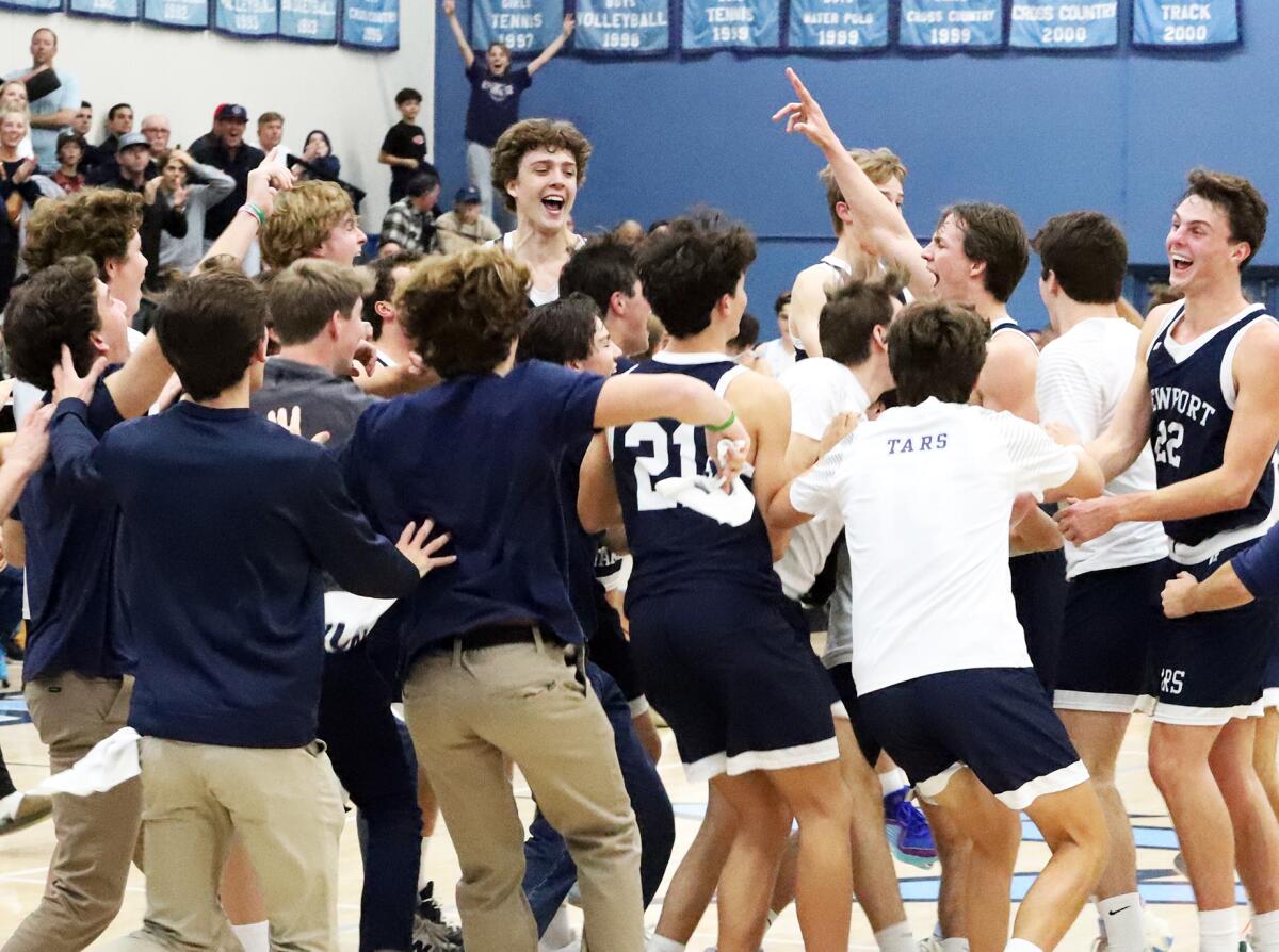 The Newport Harbor boys' basketball team is mobbed by fans at midcourt after beating rival Corona del Mar on Saturday.