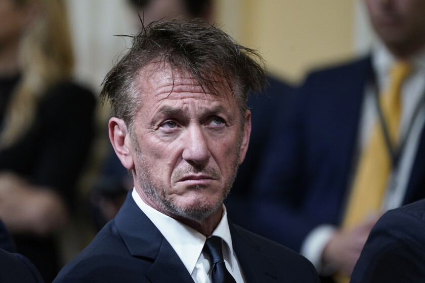 Sean Penn, wearing a suit, looks into the distance.