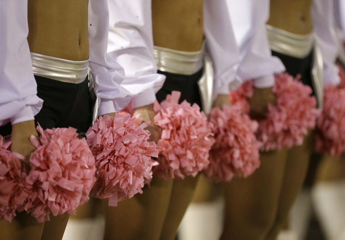 Oakland Raiders cheerleaders hold pink pom-poms for breast cancer awareness before an NFL football game between the Raiders and the San Diego Chargers in Oakland on Oct. 6, 2013.