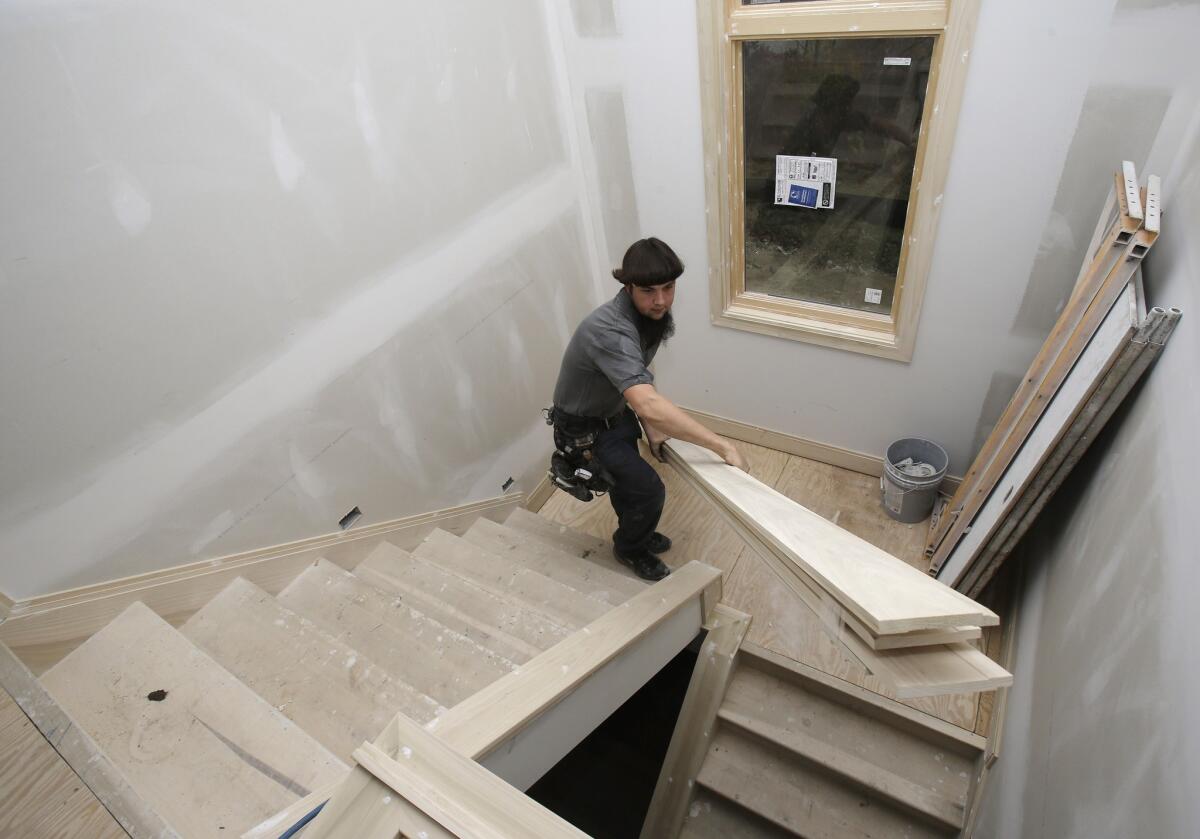 U.S. residential building permits hit a five-year high in October, the Commerce Department reported Tuesday. Above, a carpenter carries trim downstairs in a new home under construction in Pepper Pike, Ohio.