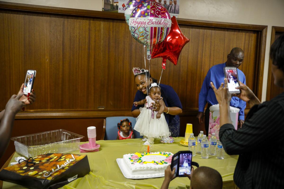 Haitian immigrant Nahomie Labady holds her 3-month-old daughter Hadassa for pictures during her birthday celebration after a Sunday service at Christ United Methodist Church. (Jay L. Clendenin / Los Angeles Times)