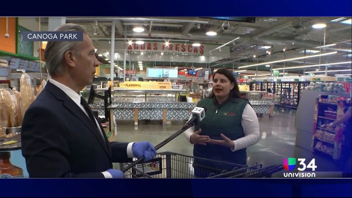 KMEX-TV 34's Oswaldo Borraez uses a long microphone to interview a grocery store customer — one of many adaptations local newscasters have made due to the coronavirus outbreak.