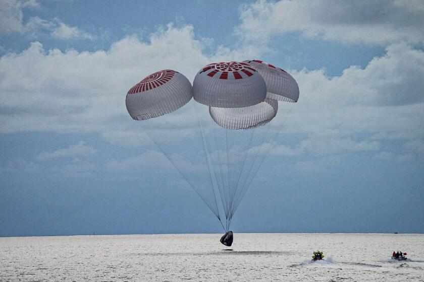 In this image taken provided by SpaceX, a capsule carrying four people parachutes into the Atlantic Ocean off the Florida coast, Saturday, Sept. 18, 2021. The all-amateur crew was the first to circle the world without a professional astronaut. (SpaceX via AP)