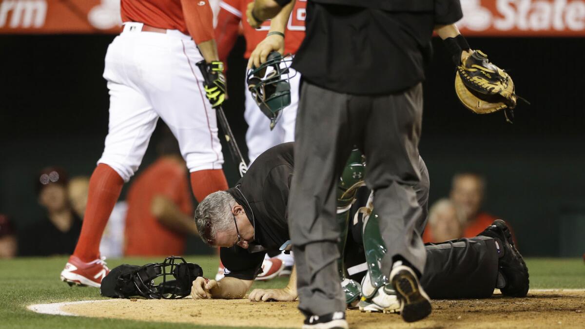 Umpire Paul Emmell stays down after being hit in the head by a bat when the Angels' Jefry Marte lost his grip during the ninth inning of Thursday's game against the Athletics.
