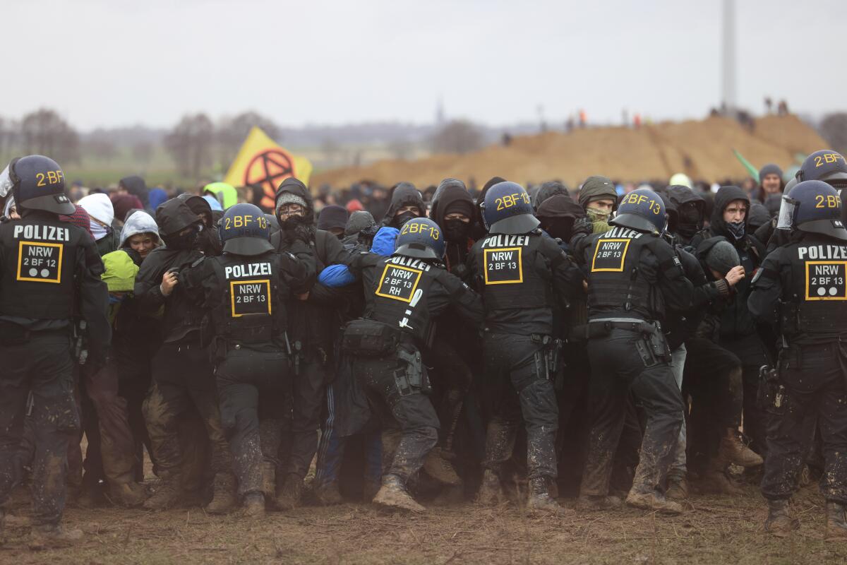 Police officers push back demonstrators on the edge of the opencast lignite mine Garzweiler at the village Luetzerath near Erkelenz, Germany, Saturday, Jan. 14, 2023. ( Oliver Berg/dpa via AP)