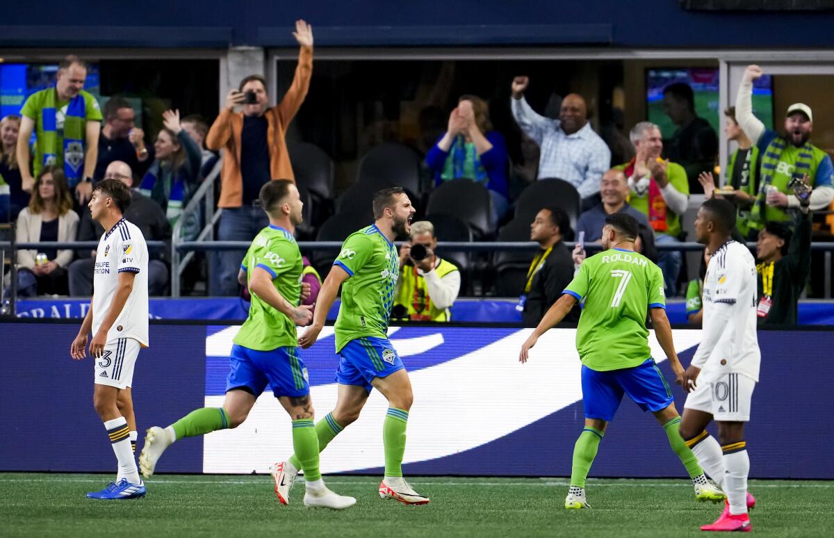 Galaxy defender Julián Aude looks toward the goal as Seattle Sounders forward Jordan Morris celebrates his goal.