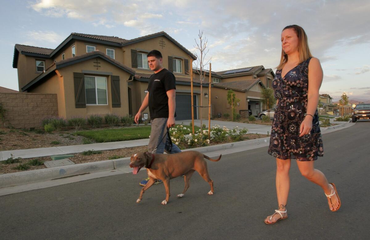 Jennifer and Patrick Kelly walk their dog Chanel down their street in Murrieta on Tuesday. — Hayne Palmour IV