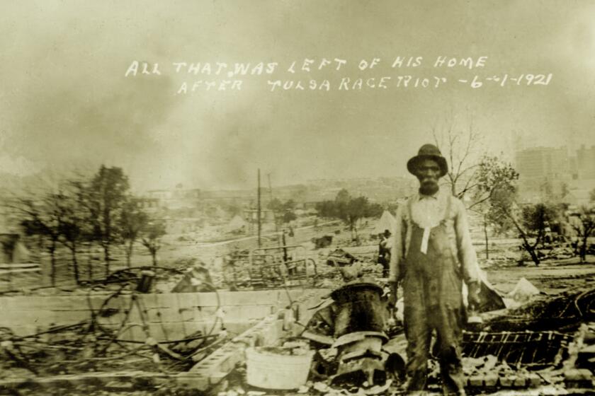 A man stands in front of what's left of his home after the destruction of the Tulsa Race Riots on June 1, 1921.
