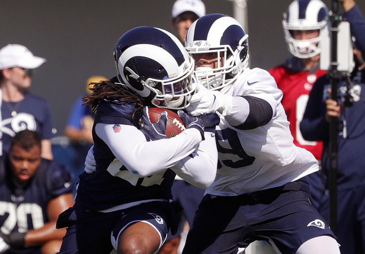  Rams running back Darrell Henderson is grabbed by the face mask by Rams defensive tackle Aaron Donald as they practice at the first day of the Los Angeles Rams training camp at UC Irvine.