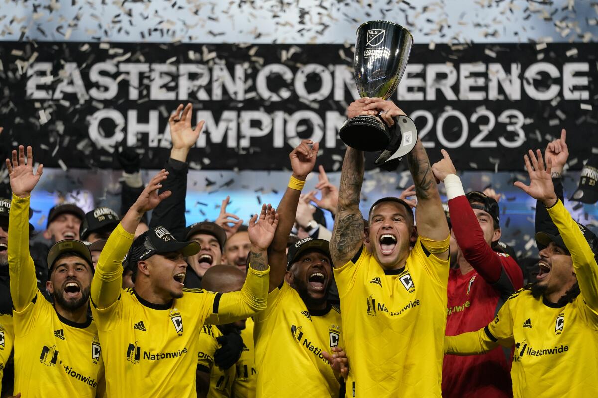 Columbus Crew forward Christian Ramírez holds up a trophy as he celebrates with teammates.