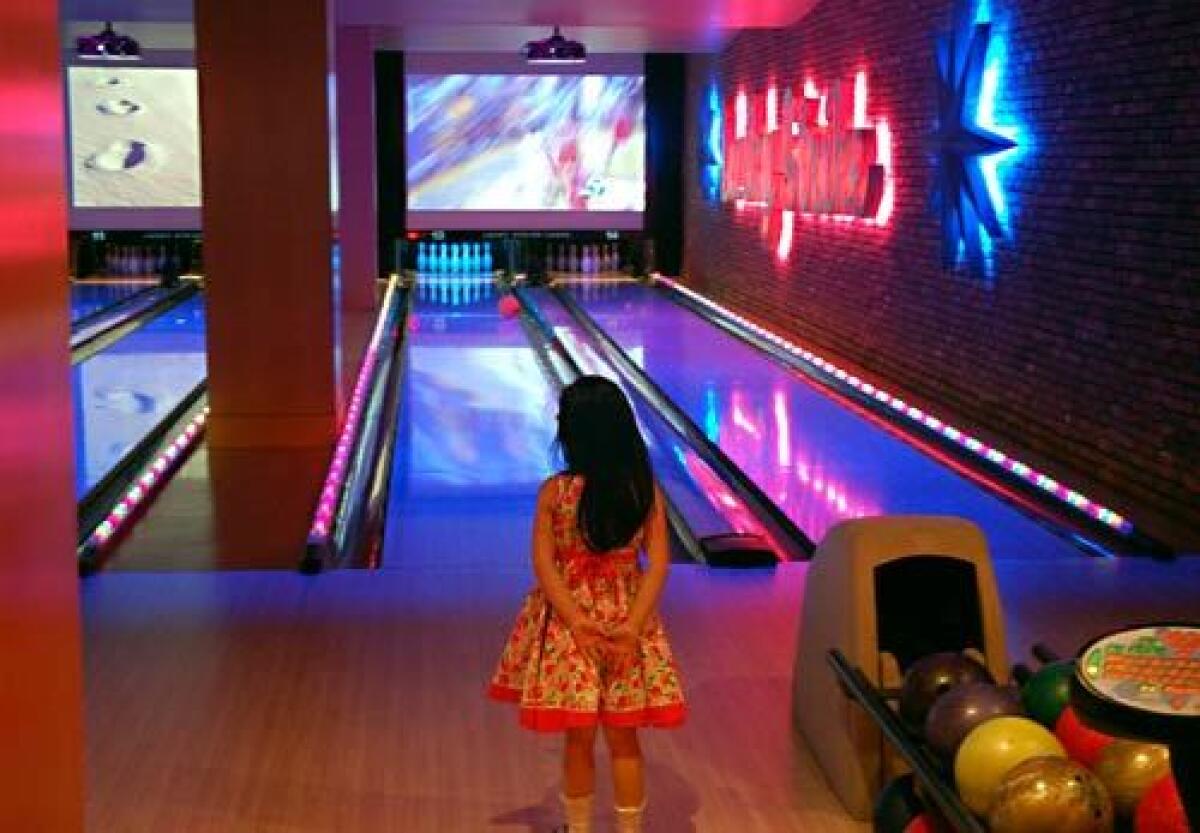A youngster surveys Lucky Strike bowling lane. By day, a family destination; at night, a club.