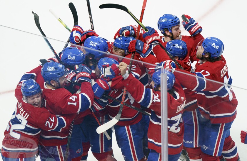 Montreal Canadiens right wing Tyler Toffoli (73) is mobbed by teammates after scoring the winning goal following overtime NHL Stanley Cup playoff hockey action against the Winnipeg Jets in Montreal, Monday, June 7, 2021. (Paul Chiasson/The Canadian Press via AP)