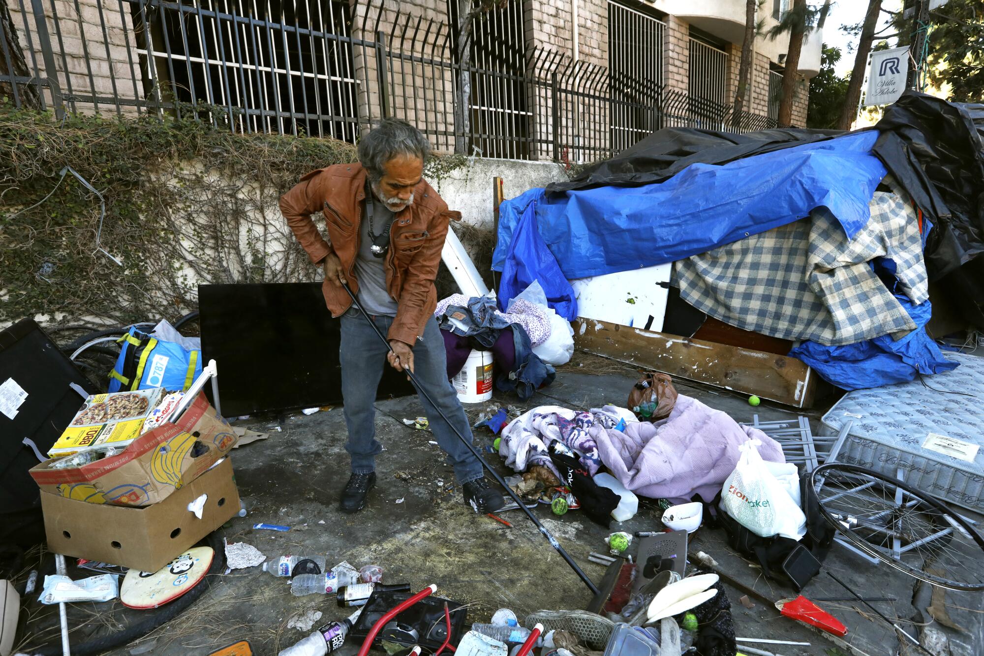 A man living on West 4th Street in Koreatown tries to clear the sidewalk