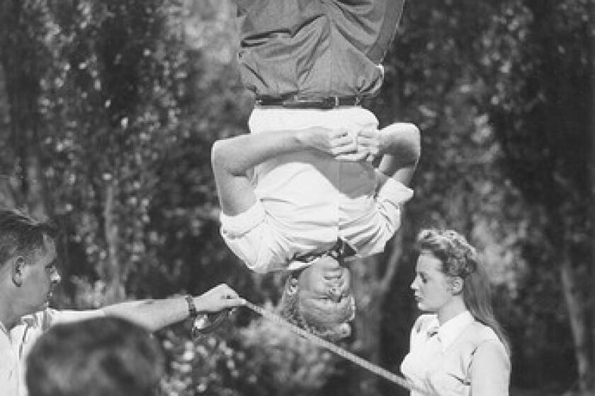 1948: Actor Van Johnson hangs from a trapeze with actress June Allyson on the ground on the set of director Norman Taurog's film "The Bride Goes Wild."