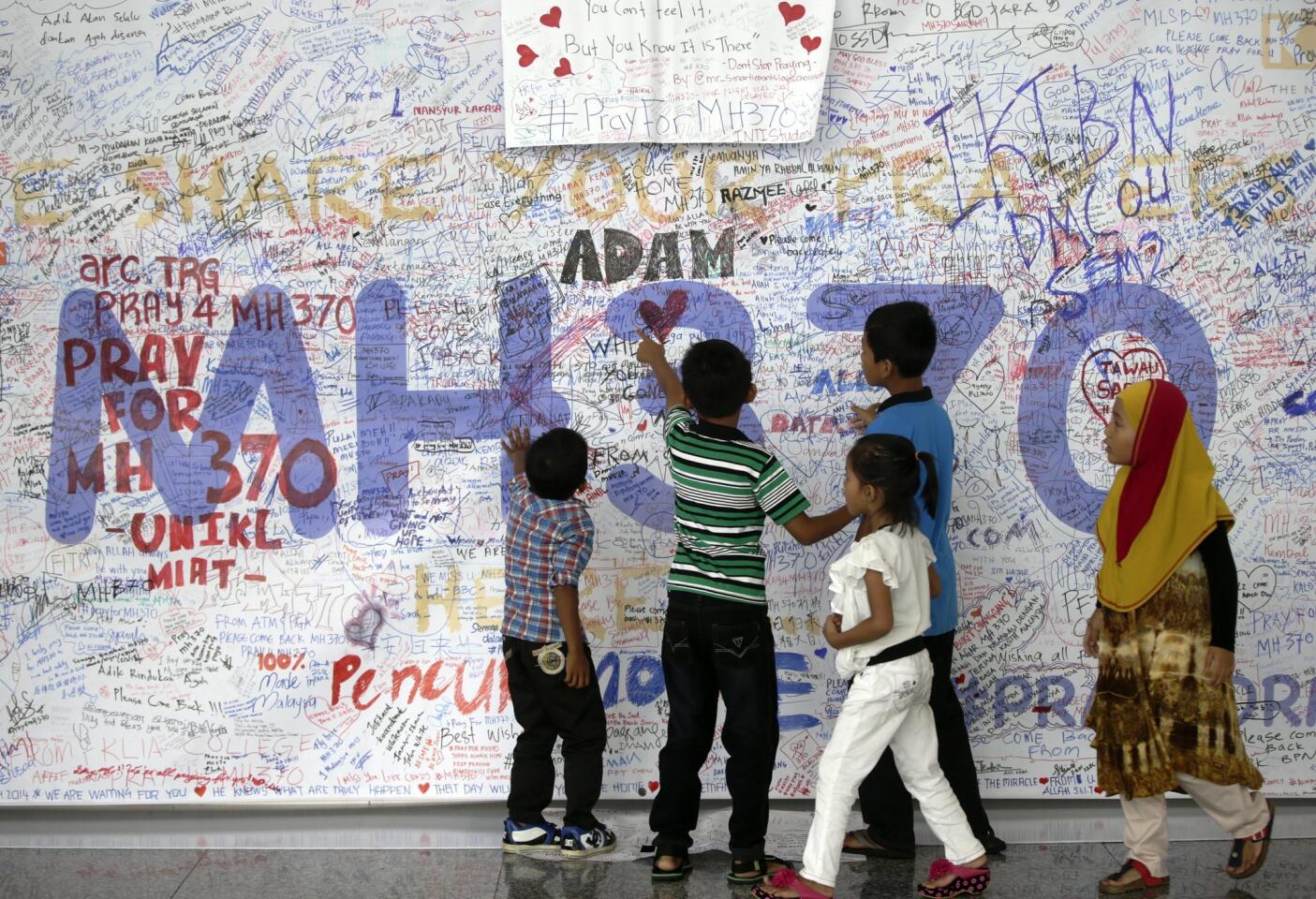 Children take at a closer look at messages on the Wall of Hope for the passengers of the missing Malaysian Airlines plane at Kuala Lumpur International Airport, Malaysia, 17 March 2014.