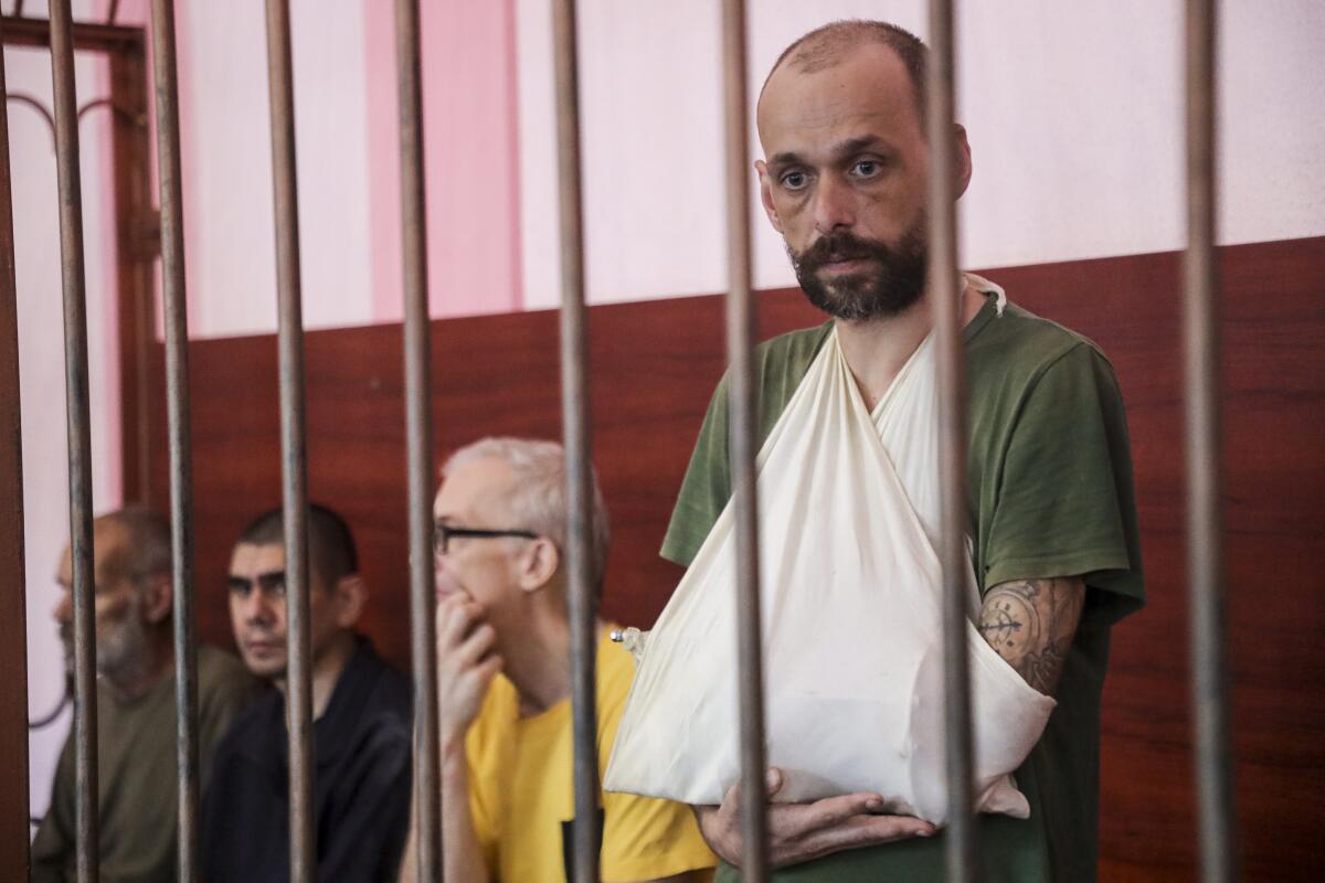 From left, British John Harding, Croatian Vjekoslav Prebeg, Swedish Mathias Gustafsson, and British Andrew Hill are seen behind bars in a courtroom in Donetsk, city in eastern Ukraine controlled by separatist authorities of the unrecognized Donetsk People's Republic, Monday, Aug. 15, 2022. The five foreign nationals who fought alongside Ukrainian forces were captured in in the eastern city of Mariupol and are standing trial on the charges of being mercenaries. (AP Photo)