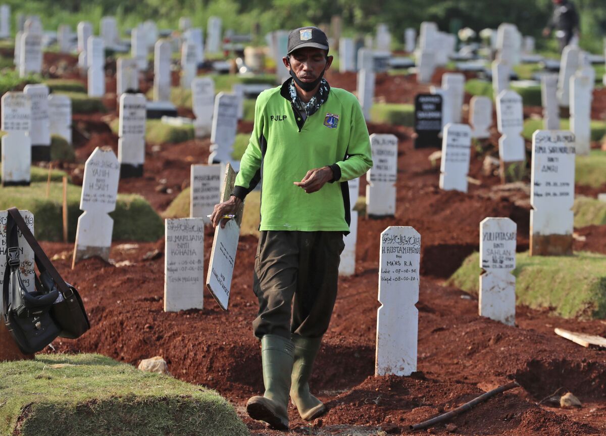 A worker walks among graves at a special cemetery for people who presumably died of COVID-19 at a cemetery in Jakarta, Indonesia Friday, June 12, 2020. As Indonesia’s virus death toll rises, the world’s most populous Muslim country finds itself at odds with protocols put in place by the government to handle the bodies of victims of the pandemic. This has led to increasing incidents of bodies being taken from hospitals, rejection of COVID-19 health and safety procedures, and what some experts say is a lack of communication from the government. (AP Photo/Achmad Ibrahim)