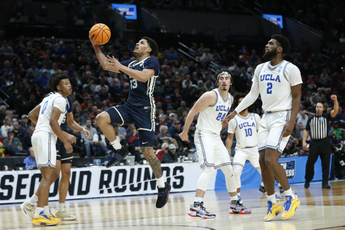 Akron guard Xavier Castaneda leaps to put up a shot as UCLA forward Cody Riley and guard Jaime Jaquez Jr. look on.