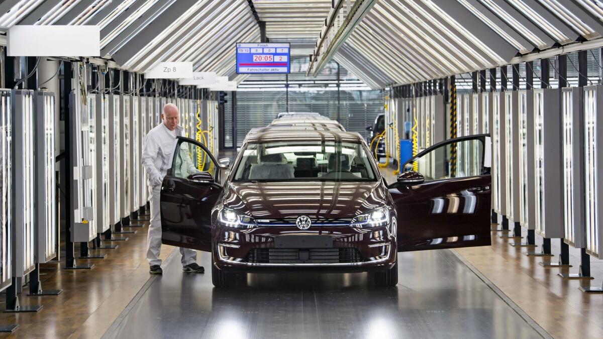 A worker performs a final check on an e-Golf electric car at a Volkswagen factory in Dresden, Germany.