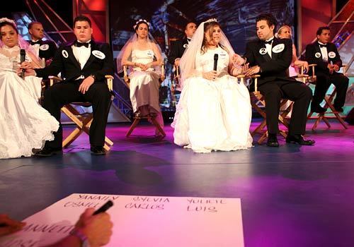 Young couples dressed as brides and grooms prepare for a "Newlywed Game"-type of contest as a production assistant scribbles down their names on cue cards for host Don Francisco. Silly game-show segments are a big part of "Sábado Gigante," and they are usually done live in front of the audience.