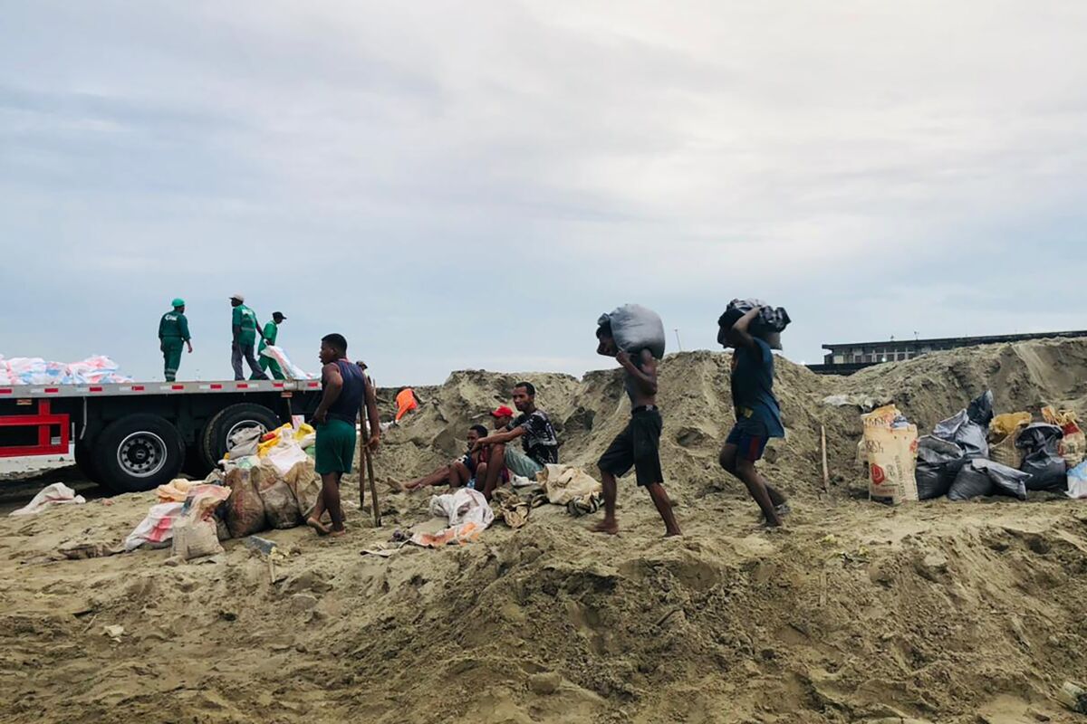 People make their way home during bad weather in Tamatave, Madagascar, Saturday, Feb. 5, 2022. Weather officials forecast that the full force of Cyclone Batsirai is to hit Madagascar Saturday evening. (AP Photo)