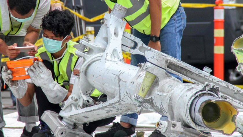 Investigators examine part of the landing gear of the Lion Air Boeing 737 MAX 8.