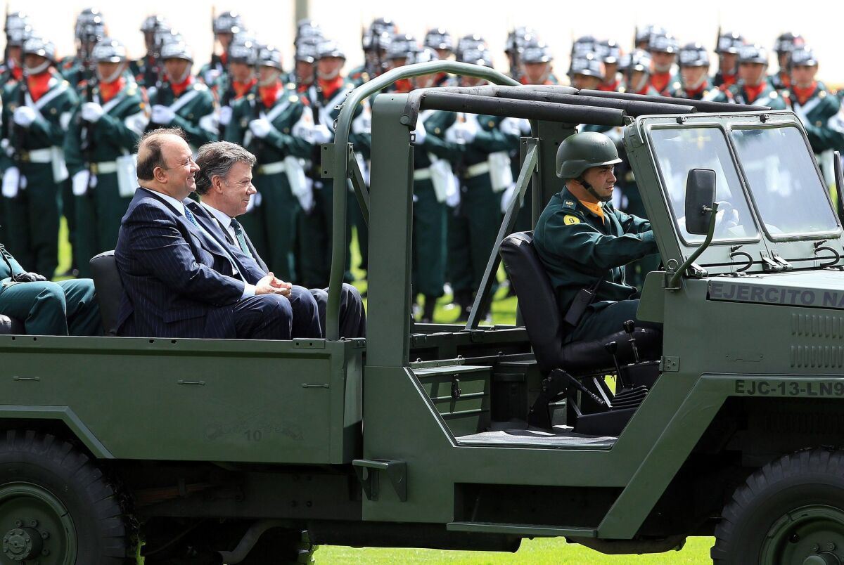 Colombian President Juan Manuel Santos, right, and new Defense Minister Luis Carlos Villegas review army troops during a military ceremony in Bogota. A new report indicates that top Colombian army brass “knew or should have known” about the extrajudicial killings of hundreds of civilians labeled as rebels.