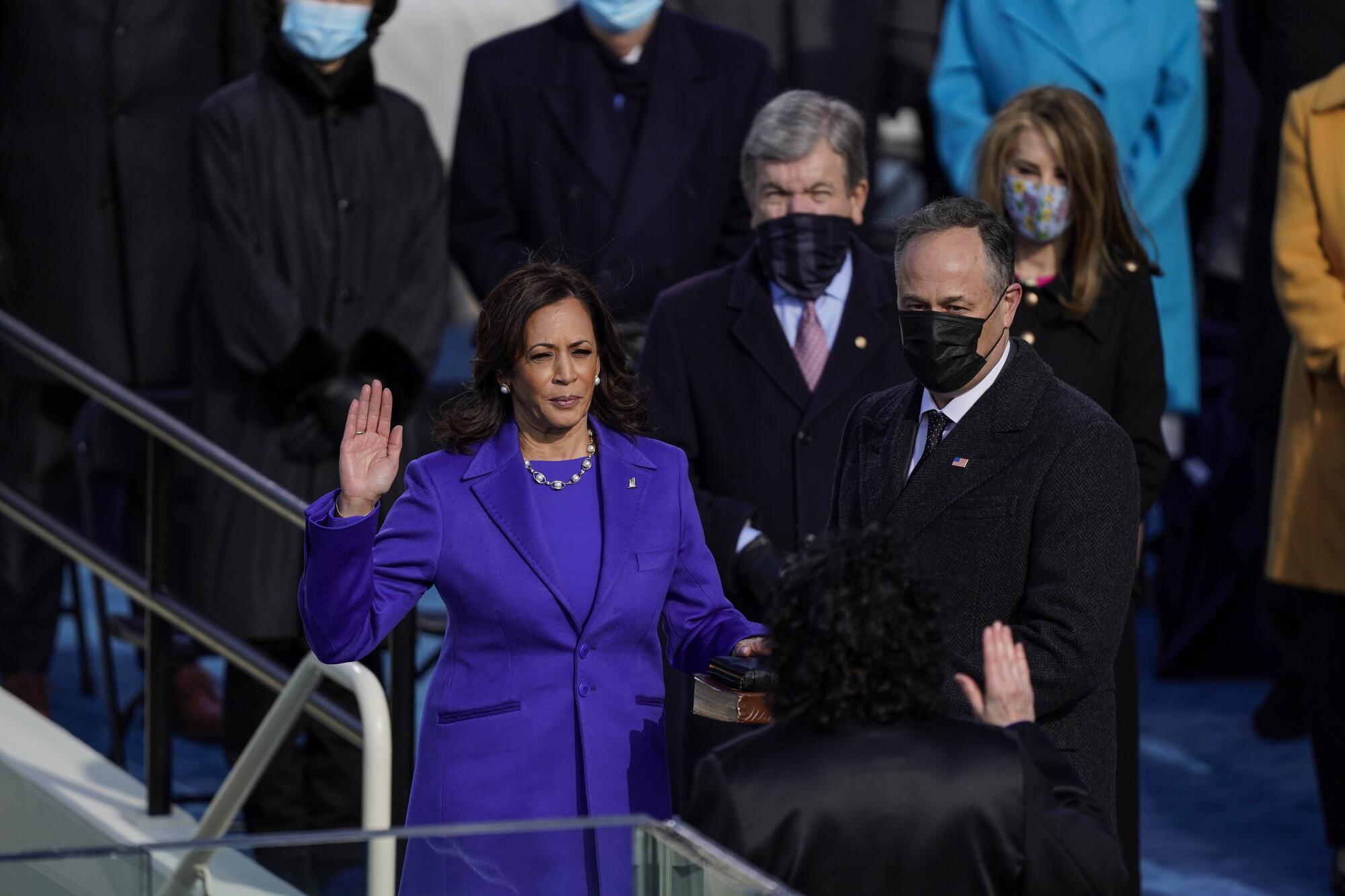 U.S. Vice President-elect Kamala Harris raises her hand to take the oath of office as Doug Emhoff stands by.