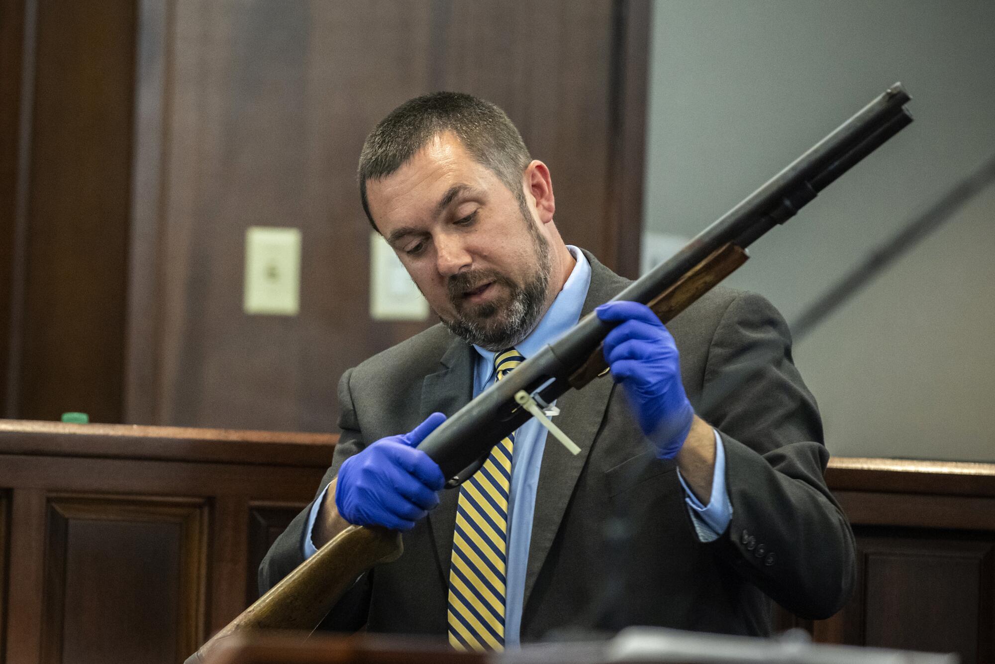 A man holds a shotgun in court.