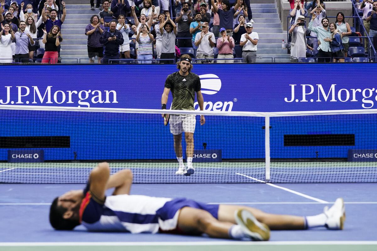 Stefanos Tsitsipas, top, walks to the net after losing to Carlos Alcaraz during the third round of the U.S. Open.