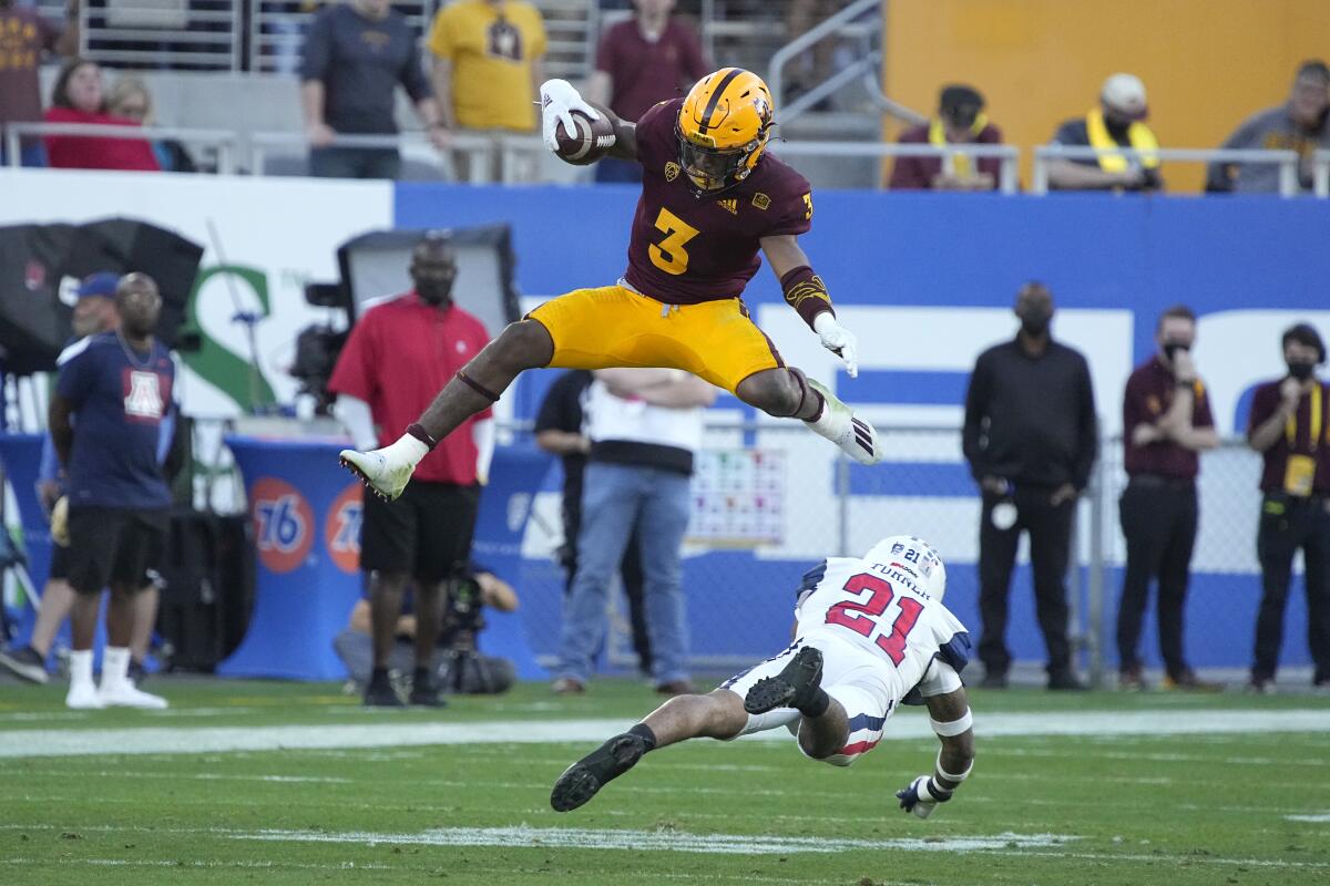 Arizona State running back Rachaad White leaps over Arizona safety Jaxen Turner.