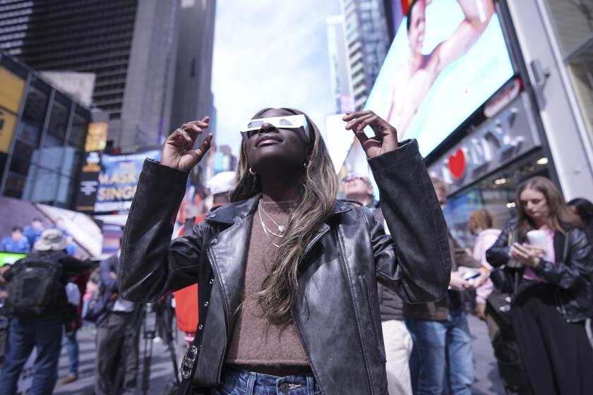 A woman views the solar eclipse in Times Square, Monday, April 8, 2024, in New York. (AP Photo/Peter K. Afriyie)