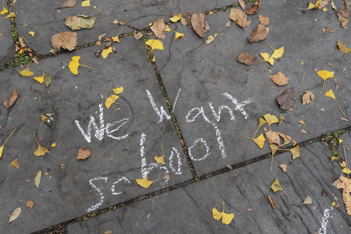 A student's chalked message, 'We want school,' is written on a sidewalk in front of New York's City Hall.