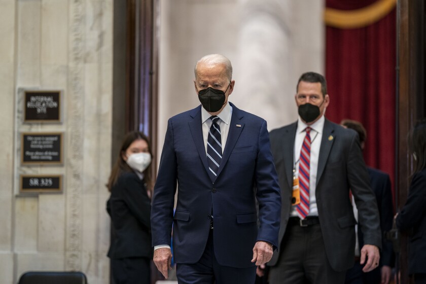 Two men in masks walk in a corridor.
