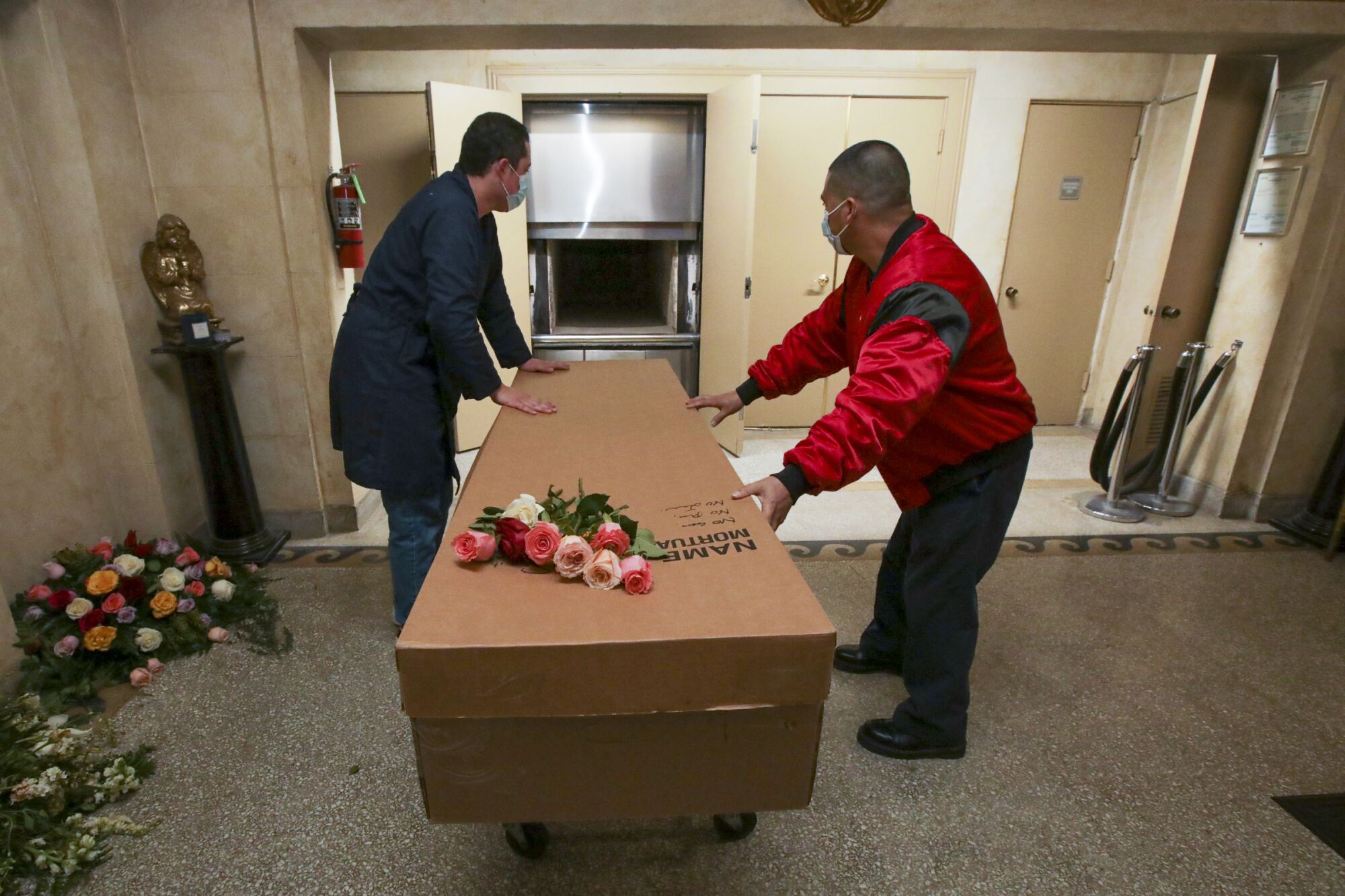 A pair of workers handle a cardboard container topped with roses