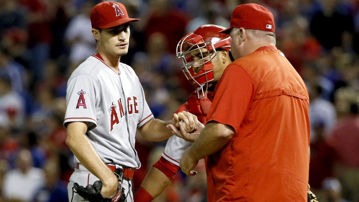 Angels starter Andrew Heaney turns the ball over to Manager Mike Scioscia in the fifth inning Thursday night in Arlington, Texas.