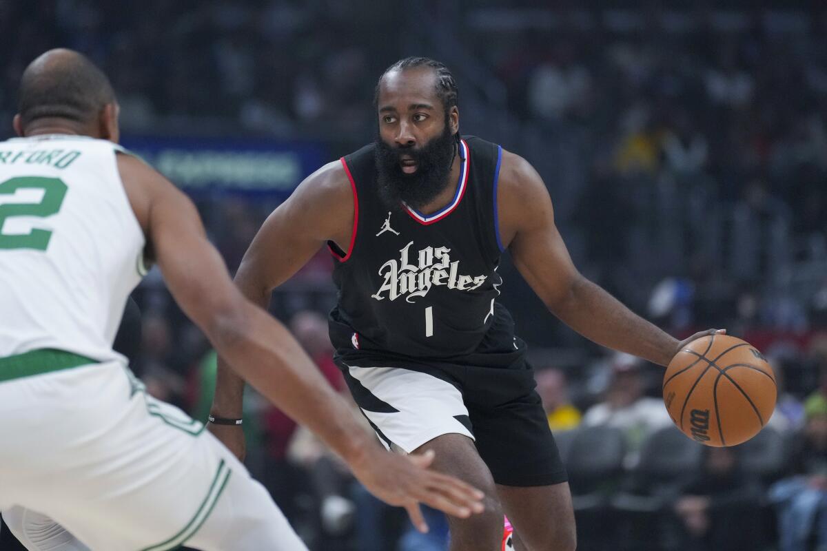 Clippers guard James Harden dribbles at the top of the key while defended by Celtics center Al Horford.