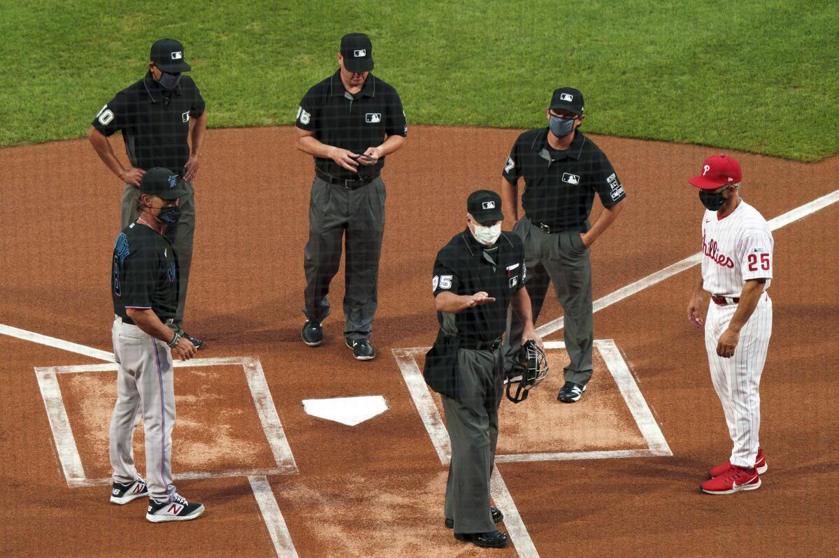 Home plate umpire Tim Timmons speaks with Marlins manager Don Mattingly and Phillies manager Joe Girardi.