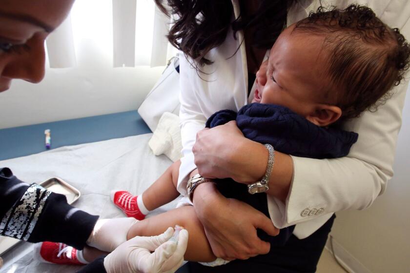 LOS ANGELES, CA-FEBRUARY 6, 2015: Medical assistant Daisi Minor, left, gives an MMR vaccine to Kristian Richard, 1, being held by his mother Natasha, at the Medical Arts Pediatric Med Group on Wilshire Blvd. in Los Angeles on February 6, 2015. (Mel Melcon/Los Angeles Times)