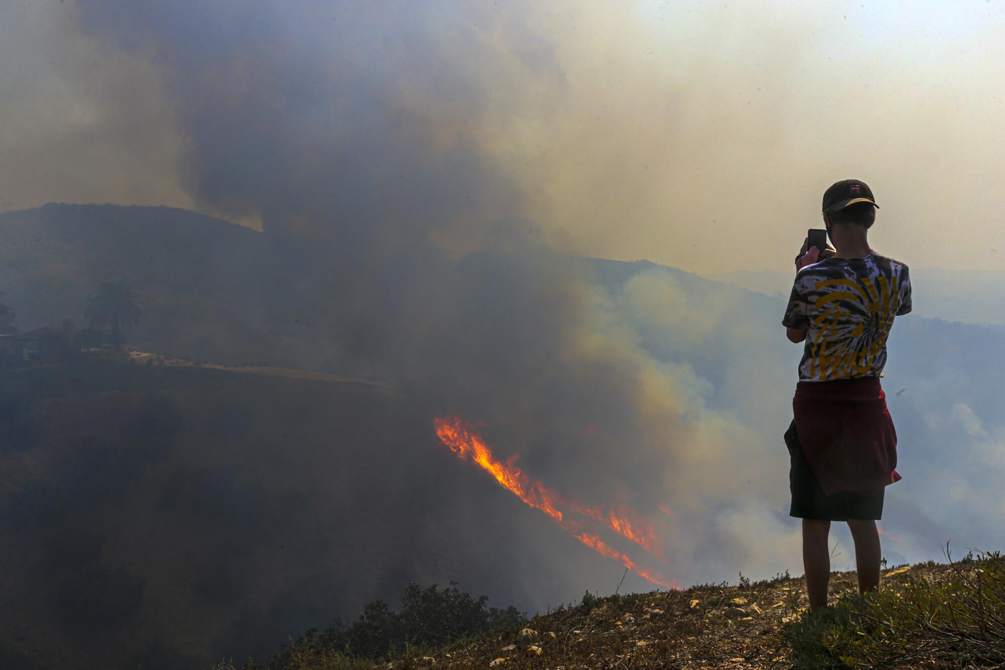 Brandon Baker watches the Blue Ridge fire burn Tuesday in a canyon along Casino Ridge Road in Yorba Linda.