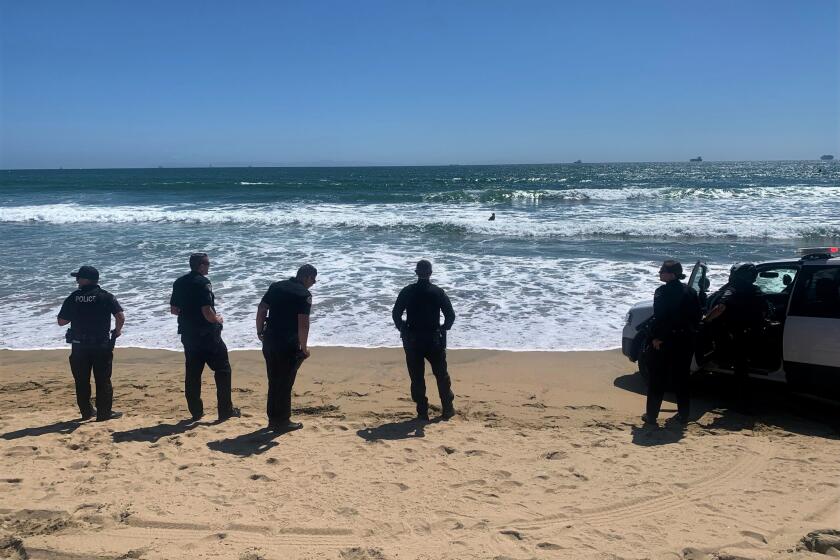  Police wait onshore at Bolsa Chica State Beach Saturday, after a robbery suspect tried to evade capture by swimming away.