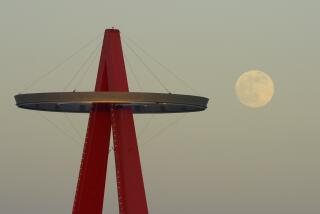 The moon rises next the Los Angeles Angels' "Big A" sign.
