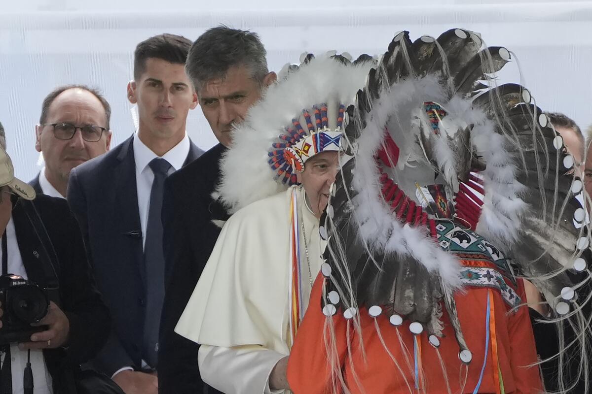 Massimiliano Strappetti, izquierda, observa cuando le colocan un tocado indígena al papa Francisco 