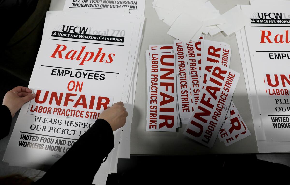 A pair of hands frames posters in support of a strike vote for grocery workers in Southern California.