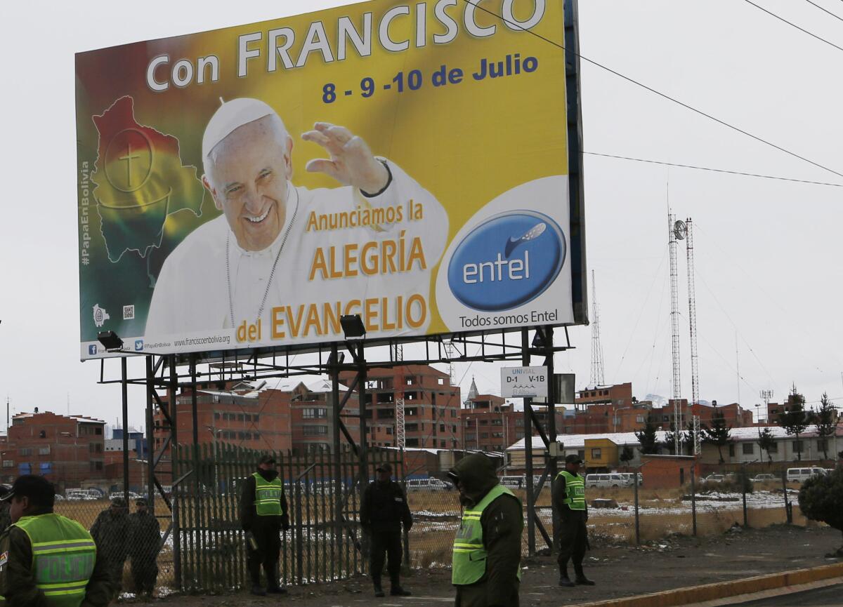 Policías montan guardia cerca de un cartel con la imagen del papa Francisco durante una maniobra previa a su llegada.