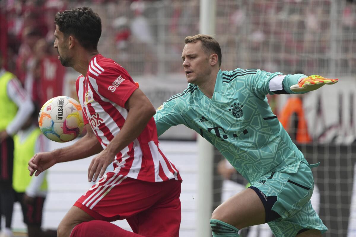 Bayern's goalkeeper Manuel Neuer, right, and Union's Rani Khedira challenge for the ball during the German Bundesliga soccer match between 1. FC Union Berlin and FC Bayern Munich at the Alte Forsterei stadium in Berlin, Germany, Saturday, Sept. 3, 2022. (AP Photo/Michael Sohn)