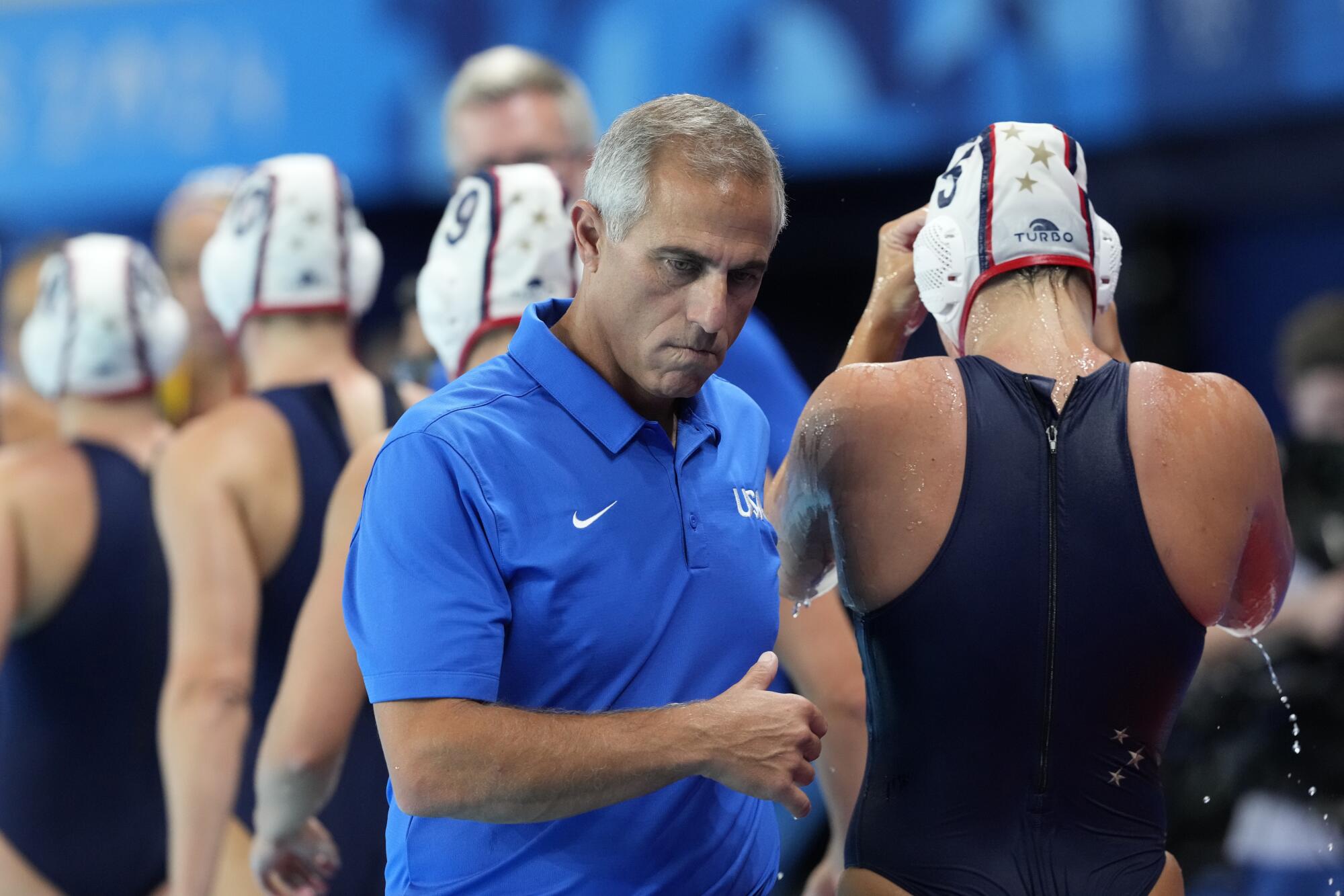 U.S. women's water polo coach walks past his players during a preliminary match against Spain on July 29.