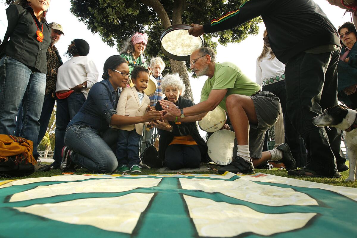 Shay White, left, and her son Elias Washington, join with activist Jerry Rubin, right, and wife Marissa to light a peace candle during an Earth Day ceremony at the Children's Tree of Life at Santa Monica Palisades Park.